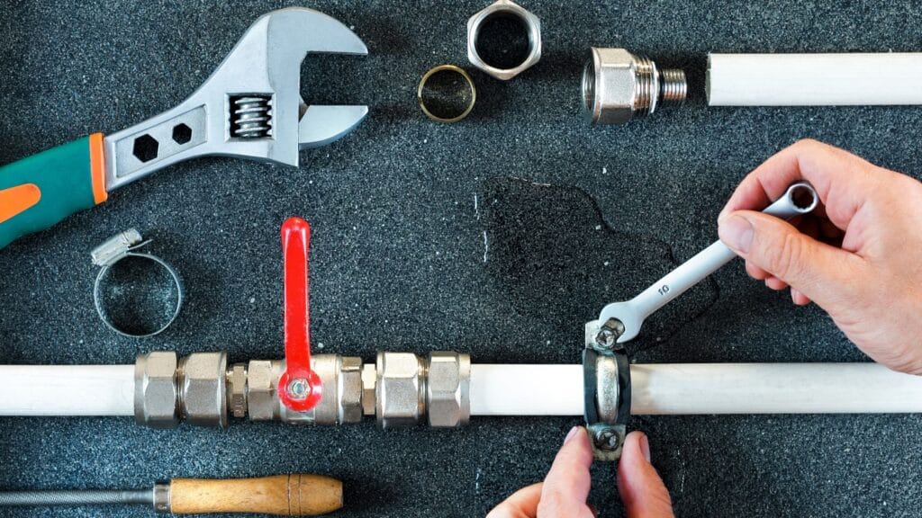 Plumber repairing a pipe valve with an adjustable wrench in Marina