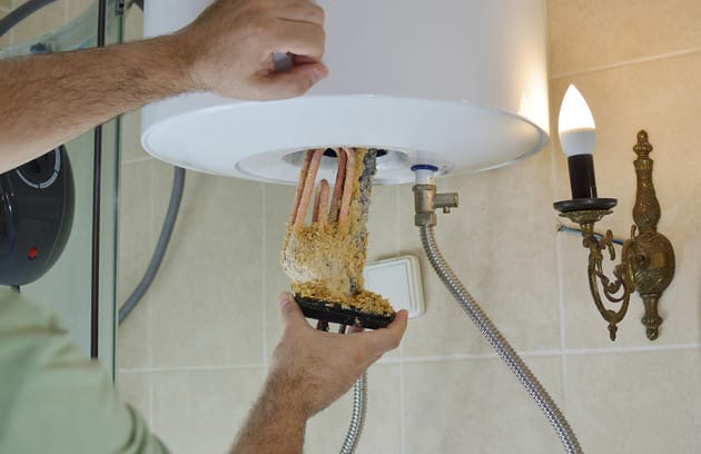 Technician removing mineral buildup from a water heater in Marina