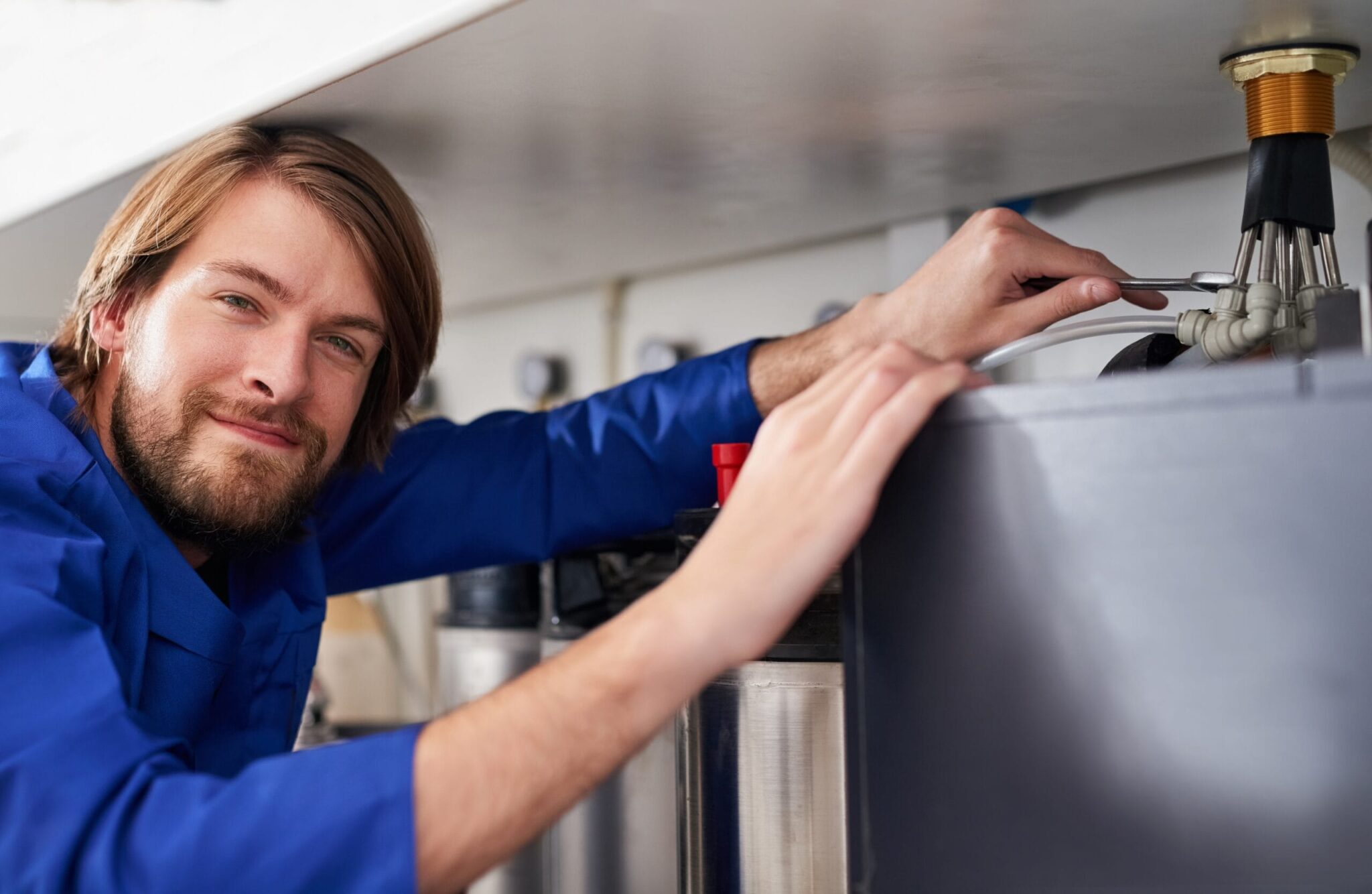 Technician servicing a residential water heater tank in Marina