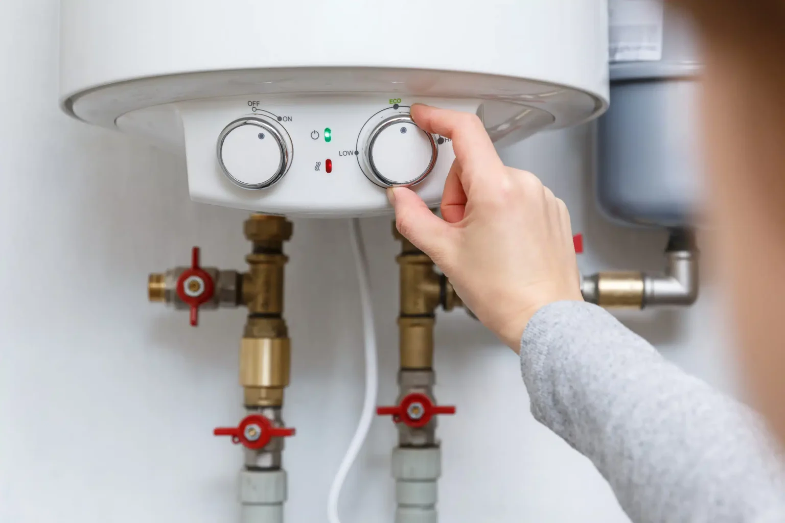 Homeowner adjusting the temperature controls on a water heater in Marina